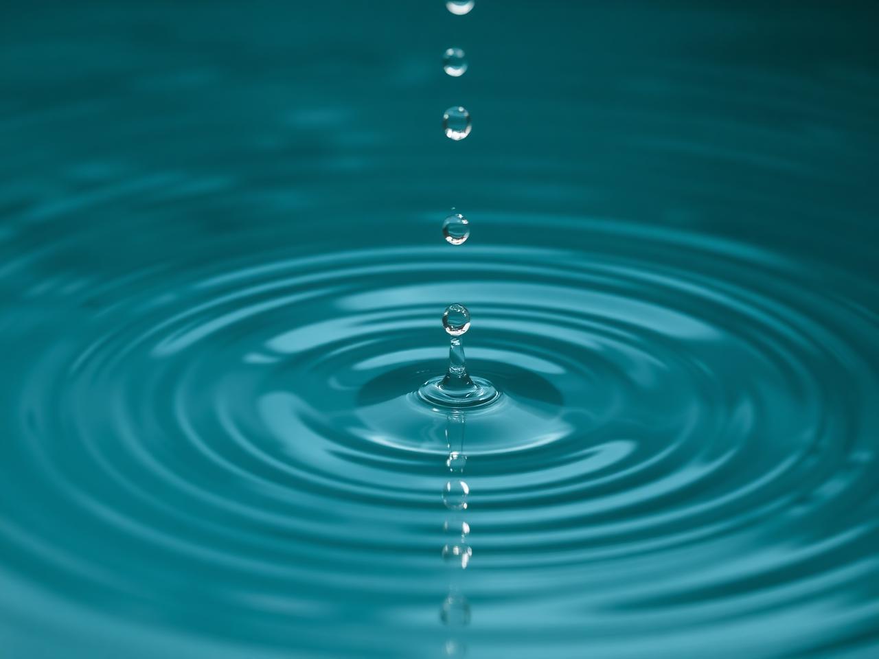 Concentric ripples spreading across calm teal water